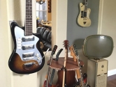 hanging guitars and rotating guitar stand next to vintage TV set