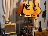 Carousel 12 guitar stand holding acoustics on the top tier, and electrics on the bottom tier, next to a collection of amplifiers
