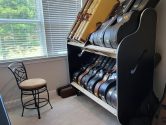 side view of guitar shelves in a well-lit room next to a stool