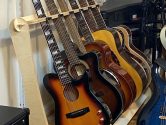 carvin guitar and other instruments resting in a wood stand