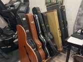wooden guitar case rack placed between an exercise bike and a desk