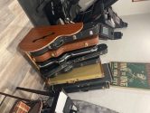 wooden guitar case rack placed between an exercise bike and a desk