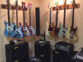 bass guitars hanging from the wall, above amplifiers