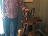 man standing next to his multi guitar stand