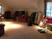 room with slanted ceiling, filled with guitars and cases