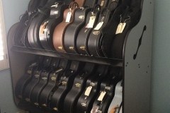 two shelves full of acoustic guitar cases