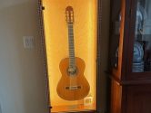 display case holding an acoustic guitar, next to a china cabinet