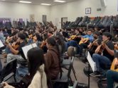 classroom full of students playing guitars in an ensemble