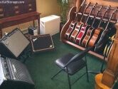 guitars and amps and a folding chair on a green carpet