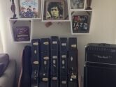 guitar case holder below pictures of musicians and next to an amplifier