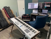 home music studio with keyboard, blue chair, guitar cases and computer monitors
