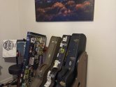Studio Standard guitar case rack against a wall, below a  painting of a mountain