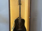 black acoustic guitar in a lit display case