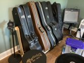 wood stand holding multiple acoustic guitar cases