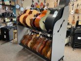two tiered shelf rack, with grey sides and wheels, holding mariachi guitars and cases