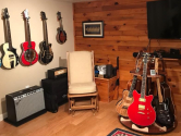 guitar stands and wall hangers in room with wood floors and cedar wall