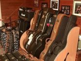 wood guitar case rack next to a wall with photos