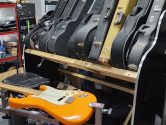 yellow stratocaster in a luthier workshop, placed next to shelves with guitar cases