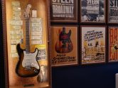 springsteen autographed guitar in lit display case next to concert posters