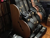 Wood Guitar Case Rack in front of a wall filled with records