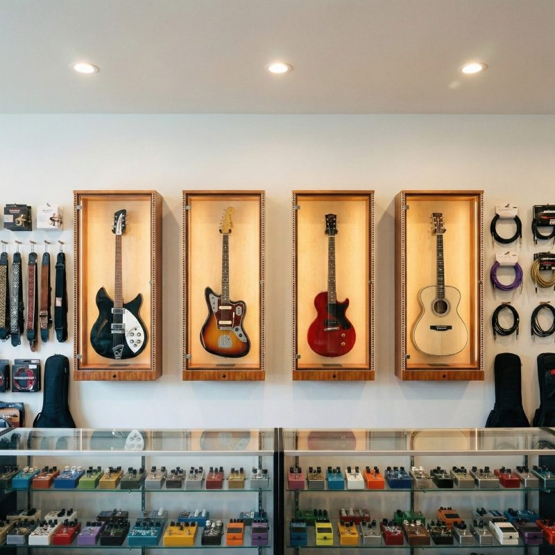 4 guitars in wooden display cabinets behind the counter at a music store