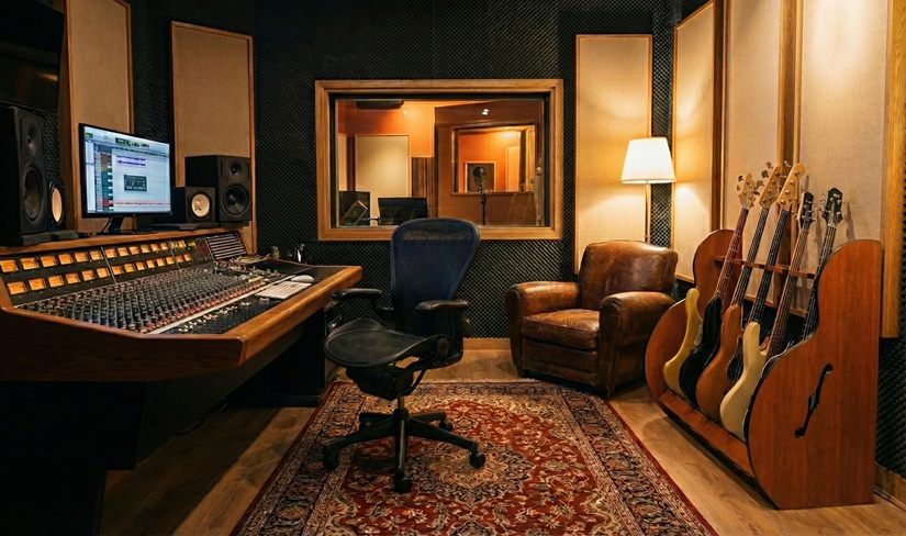 recording studio with console, lamps, leather chair and guitar rack